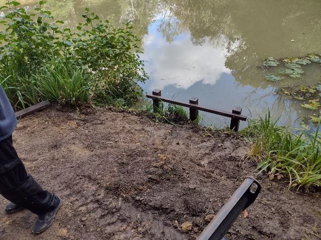Construction of two fishing platforms on a small lake surrounded by lush green foliage.