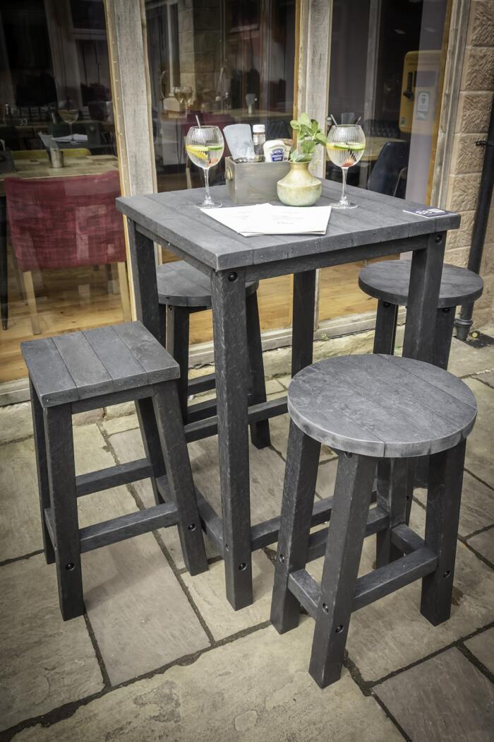 Grassington Poser table with stools in black in sitiu Poseur table and 4 stools from British recycled plastic - grey with 4 legs. 4 Round and Square stools/ Located at a hospitality venue