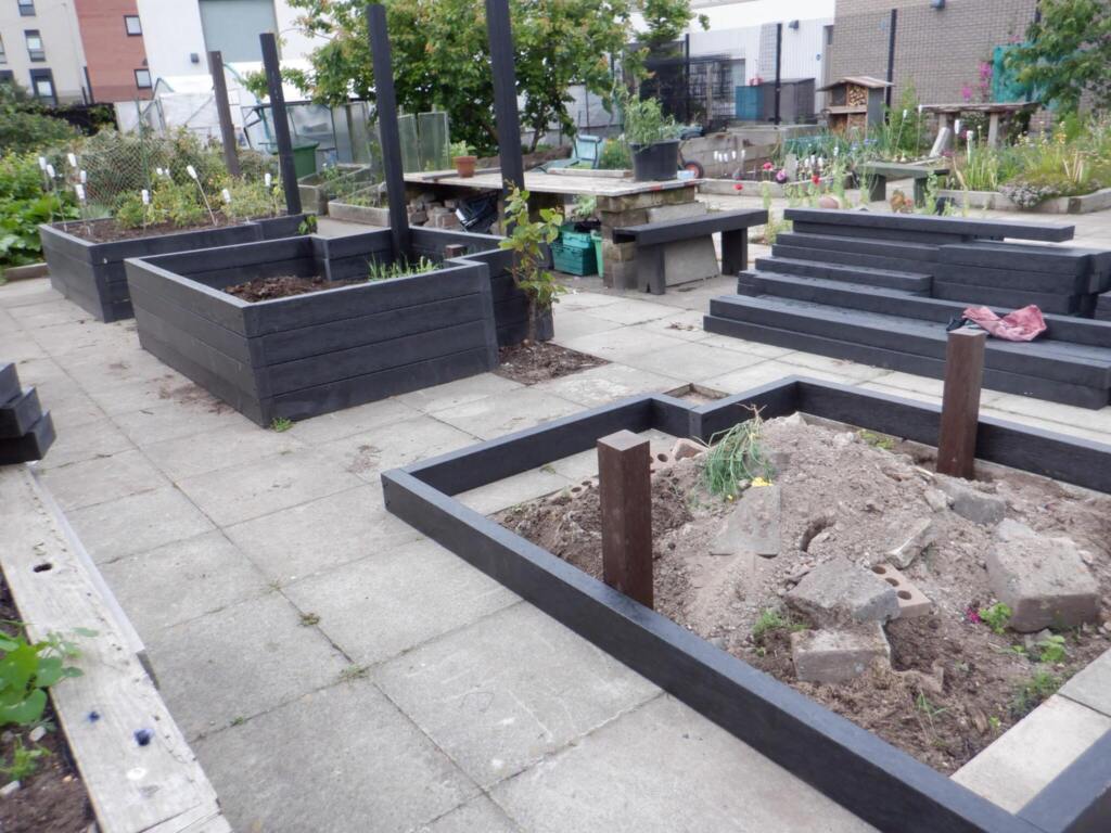 Black artificial lumber being used to make raised beds