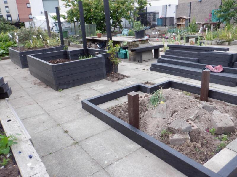 Black artificial lumber being used to make raised beds