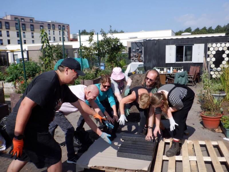 people bending down picking up British Recycled Plastic black lumber