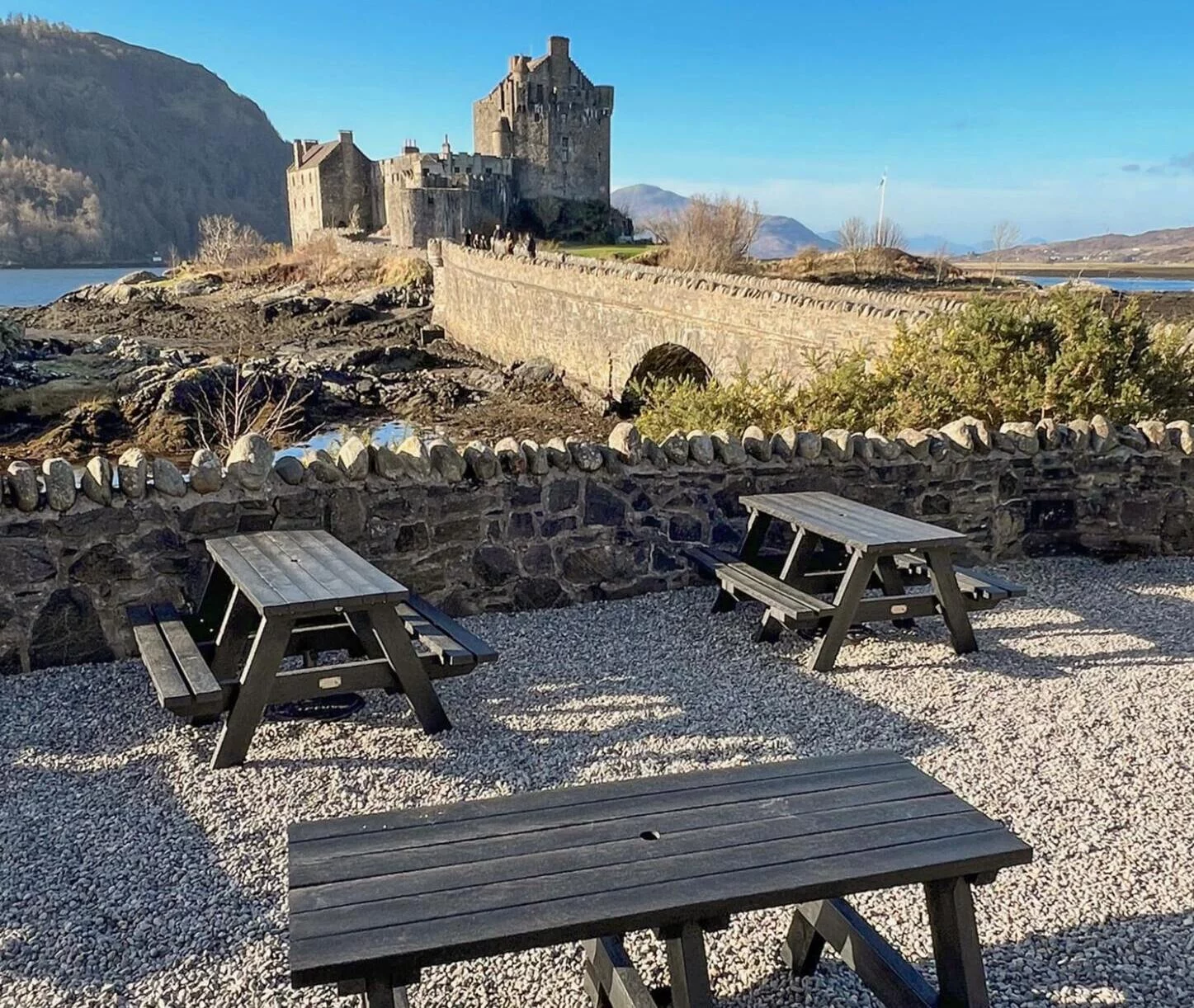 picnic tables in front of a castle and bridge