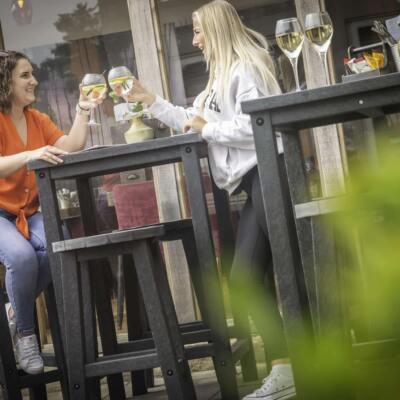 Two people enjoying a drink sat on the Grassington high top poseur table set