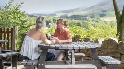 2 ladies enjoying a drink sat at a British Recycled Plastic Picnic Table