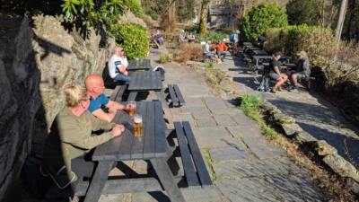 Beer garden with people enjoying the sunny weather sat on black recycled plastic picnic tables