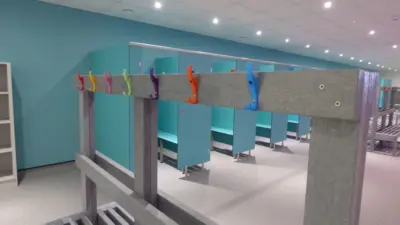 Colourful hooks on a grey bench in a swimming pool changing room.
