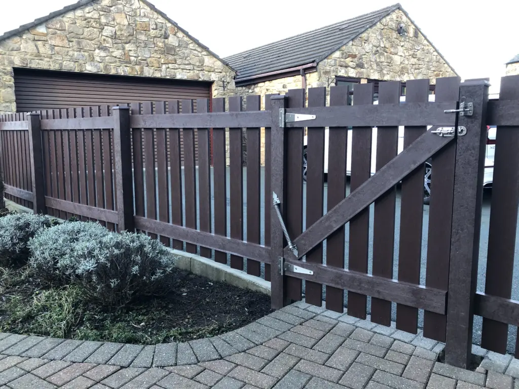 A residential home fence and gate made from 100% recycled plastic, with metal locks and fixtures.