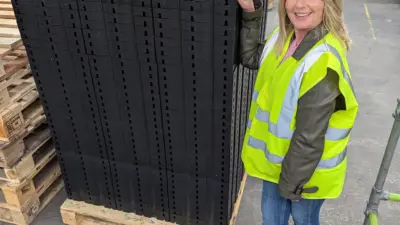 Staff next to recycled plastic permeable paving grids (Nat)